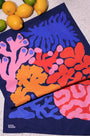 Colorful coral-patterned towel on a textured surface with lemons in the background