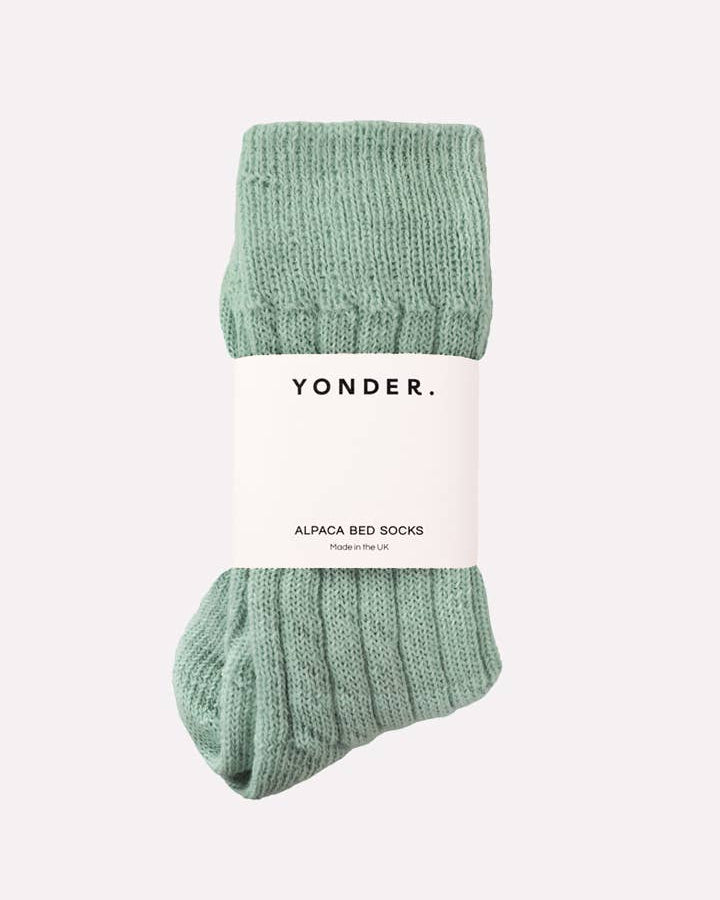Green alpaca bed socks with 'Yonder' label on a white background
