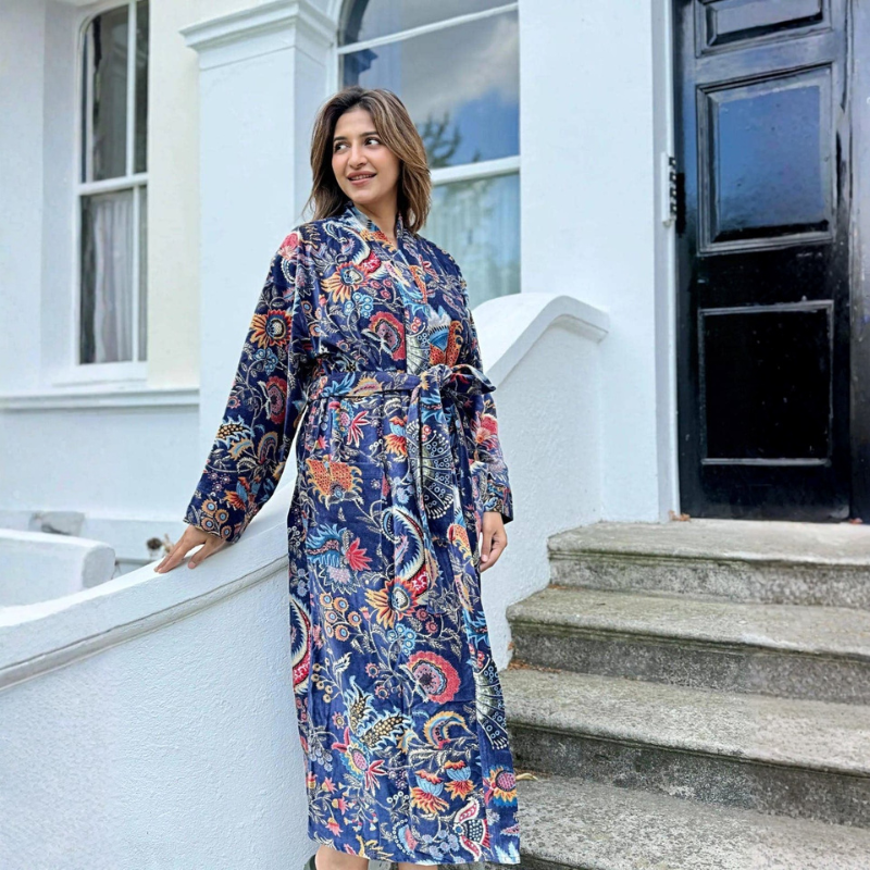 Woman wearing a floral robe standing on steps outside a house.