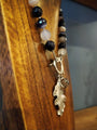 Beaded bracelet with an oak leaf charm on a wooden surface