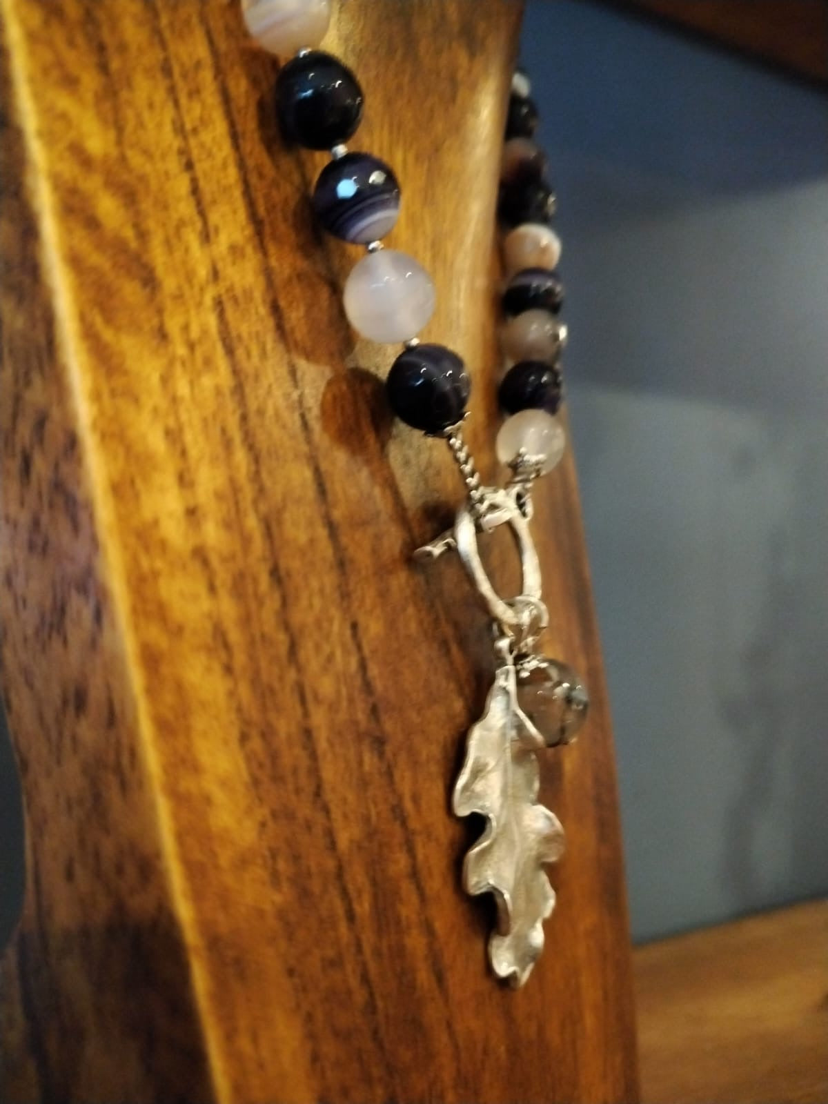 Beaded bracelet with an oak leaf charm on a wooden surface