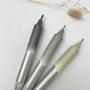 Three metallic markers on a light surface with dried plants.