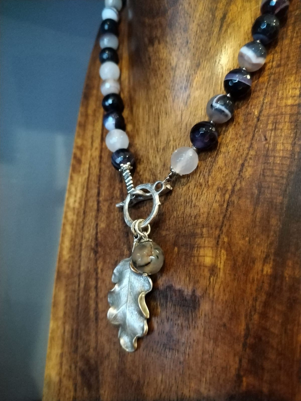 Necklace with leaf charm on a wooden surface