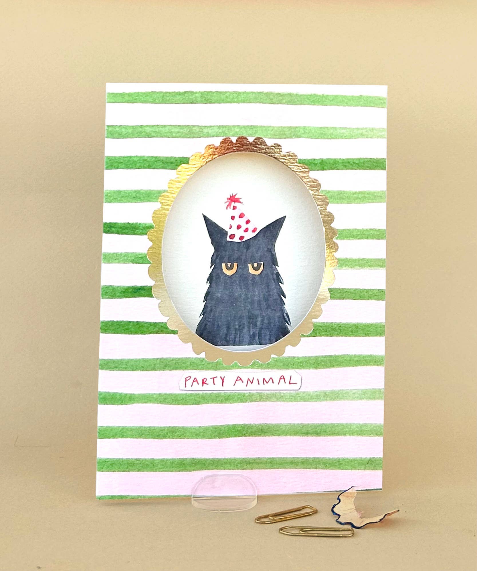 Card with a cat wearing a party hat on a striped background