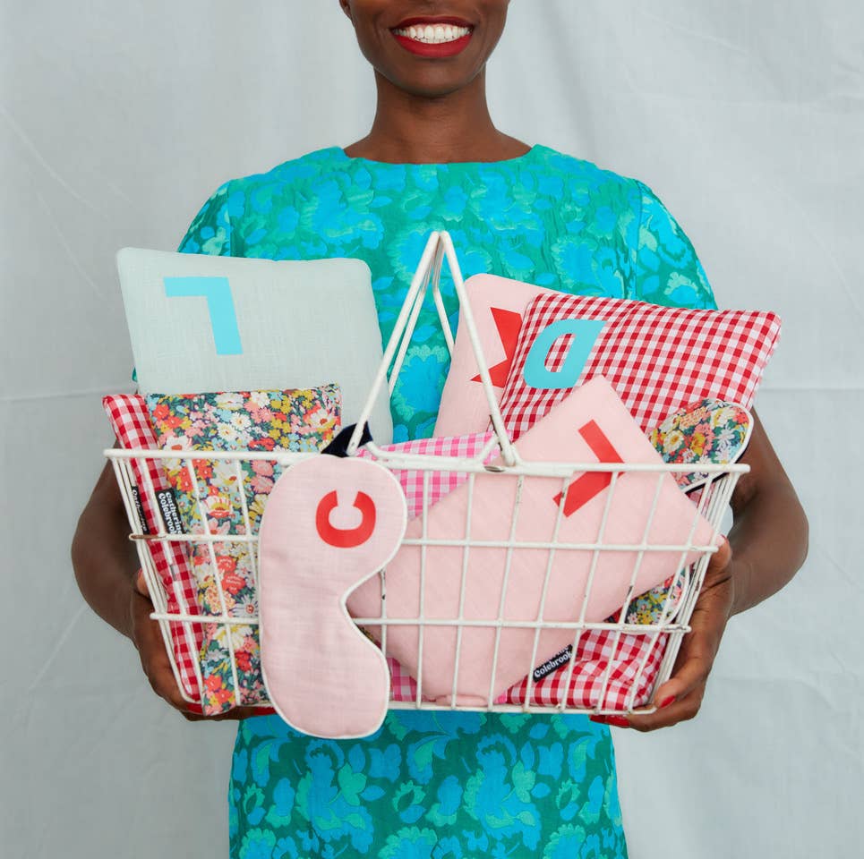 Person holding a basket of decorative pillows with colorful patterns and numbers.