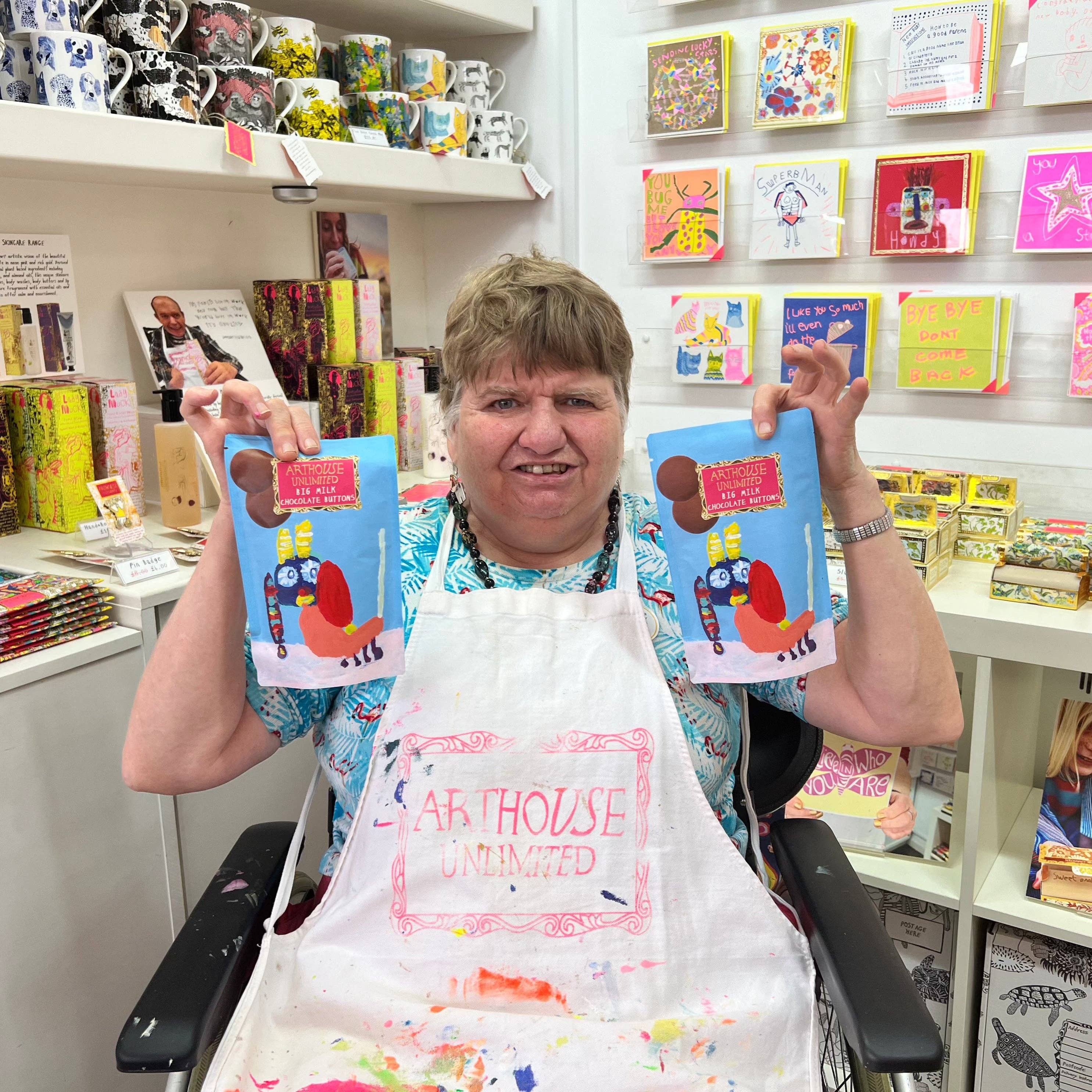 Person holding two books in a store with shelves of products in the background