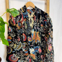 Colorful floral-patterned garment on a hanger against a white wall.