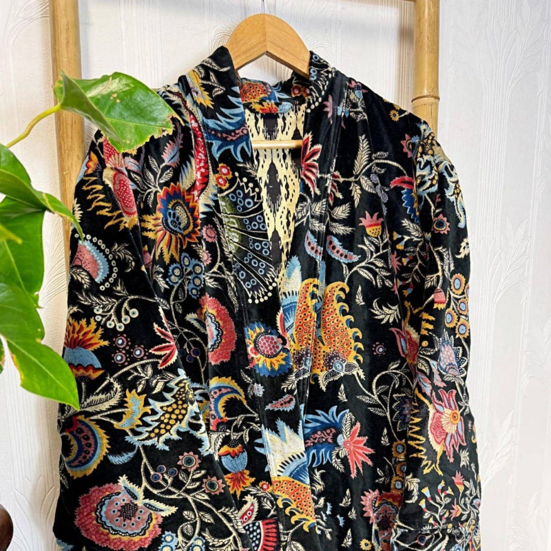 Colorful floral-patterned garment on a hanger against a white wall.
