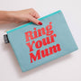 Light blue pouch with 'Ring Your Mum' text held by a hand on a white background