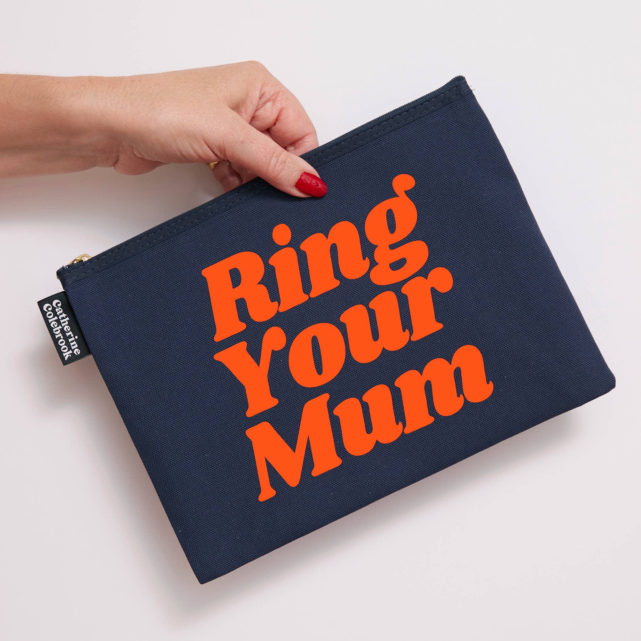 Navy pouch with 'Ring Your Mum' text held by a hand on a light background
