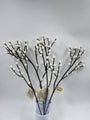 Decorative branches with white berries in a clear container on a light gray background