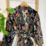 Colorful floral-patterned jacket on a wooden hanger against a white background