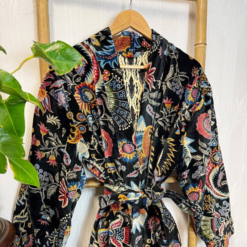 Colorful floral-patterned jacket on a wooden hanger against a white background