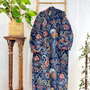 Colorful patterned robe hanging on a wooden stand against a white wall.