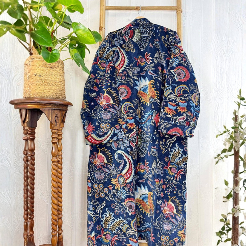 Colorful patterned robe hanging on a wooden stand against a white wall.