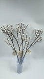 Decorative branches with white buds in a blue vase on a light gray background