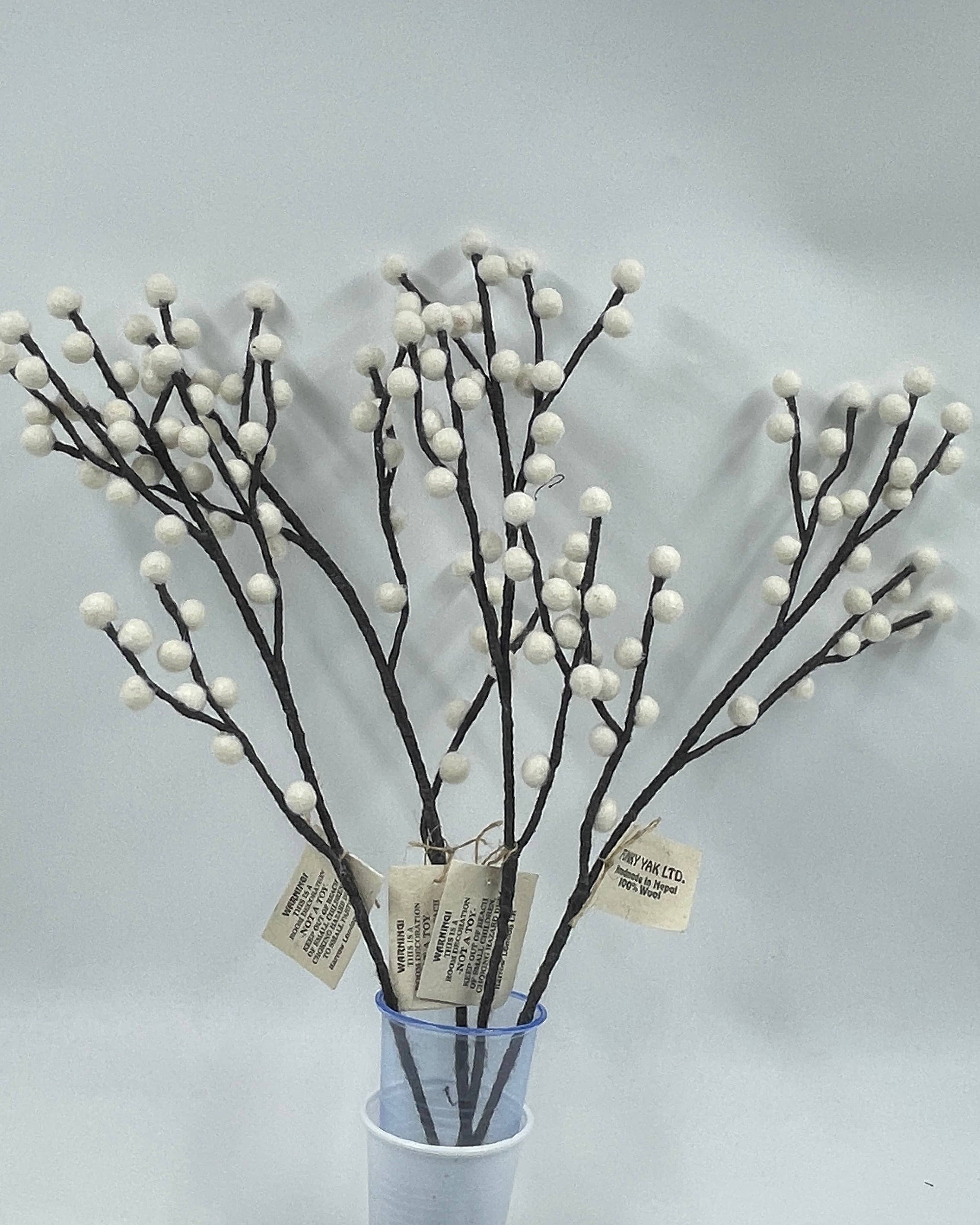 Decorative branches with white buds in a blue vase on a light gray background