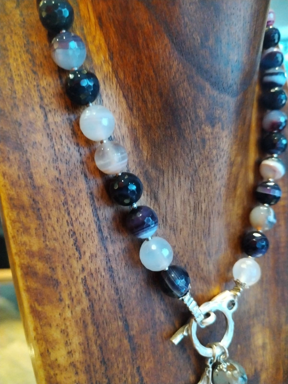 Necklace with beads and a key-shaped clasp on a wooden surface