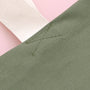 Close-up of green fabric with stitching detail on a pink background