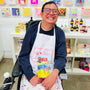 Person wearing a colorful apron in an art studio setting