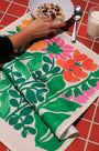 Colorful floral-patterned tablecloth on a red tiled table with a bowl of cereal.