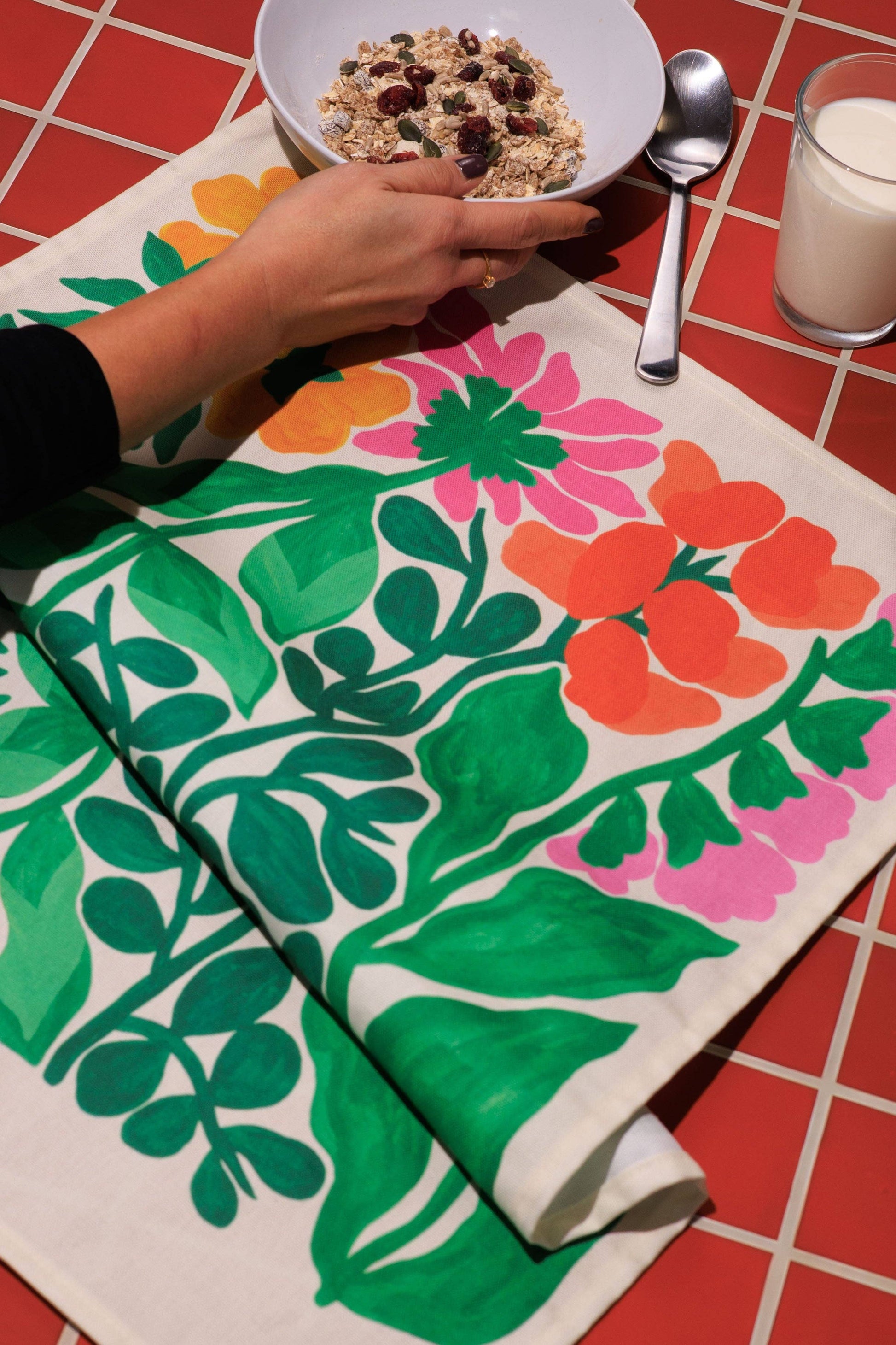 Colorful floral-patterned tablecloth on a red tiled table with a bowl of cereal.
