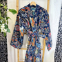 Colorful patterned robe hanging on a wooden chair with a white curtain background