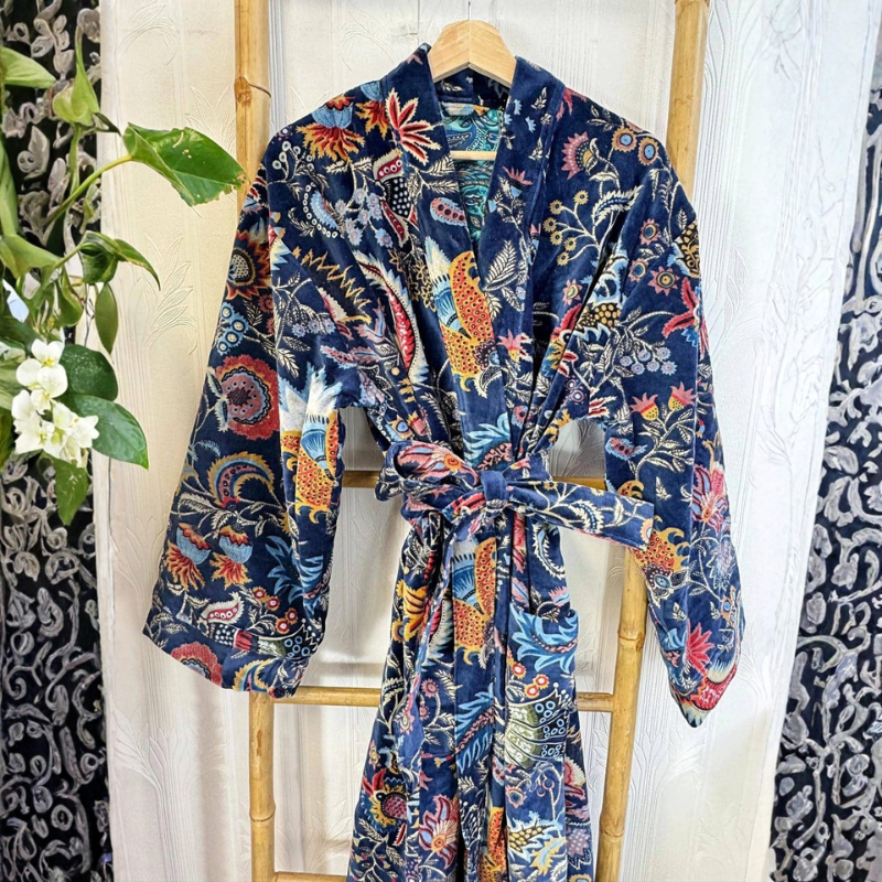 Colorful patterned robe hanging on a wooden chair with a white curtain background