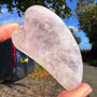 Heart-shaped crystal held by a hand with a car and trees in the background
