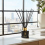 Black and gold diffuser on a windowsill with a cityscape view
