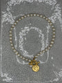 Full view of freshwater pearl necklace with gold Roman coin and T-bar clasp laid flat
