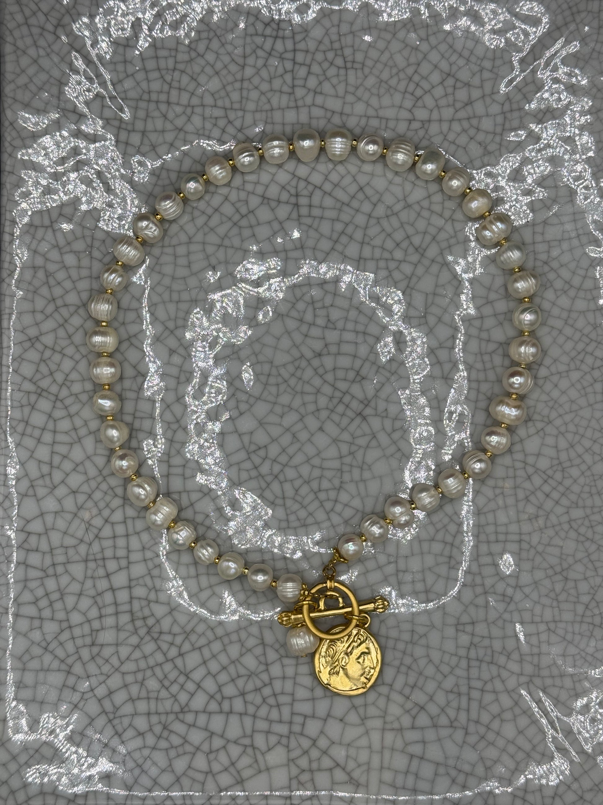 Full view of freshwater pearl necklace with gold Roman coin and T-bar clasp laid flat