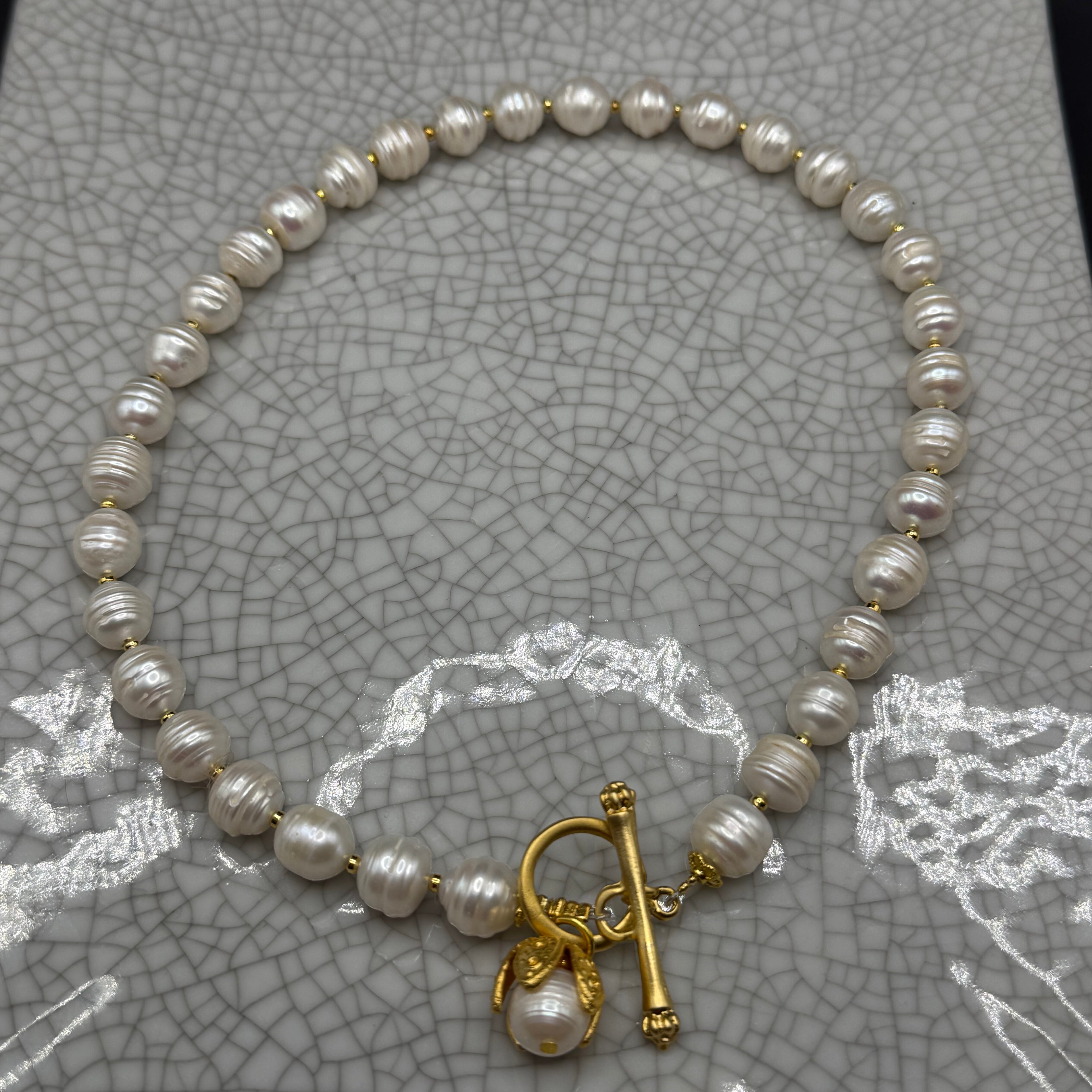 Freshwater pearl necklace with gold spacers, front T-bar clasp and pearl drop in a gold petal bud, handmade in Bristol