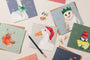 Collection of Christmas-themed greeting cards with animals on a white surface.