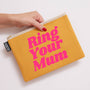 Yellow pouch with 'Ring Your Mum' text held by a hand on a light background