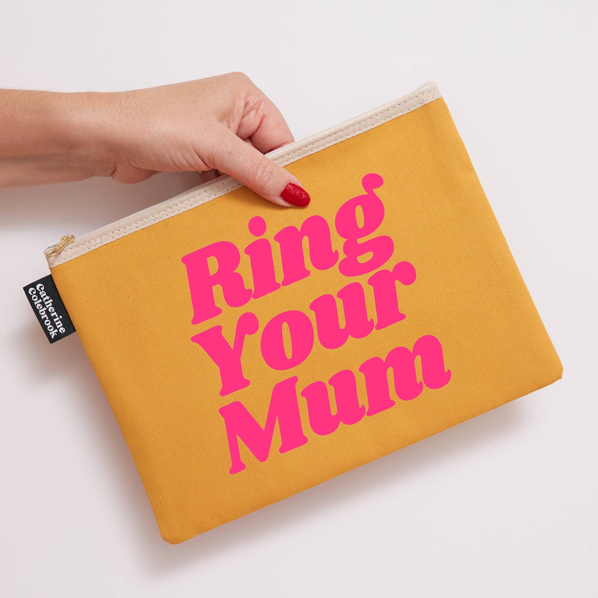 Yellow pouch with 'Ring Your Mum' text held by a hand on a light background