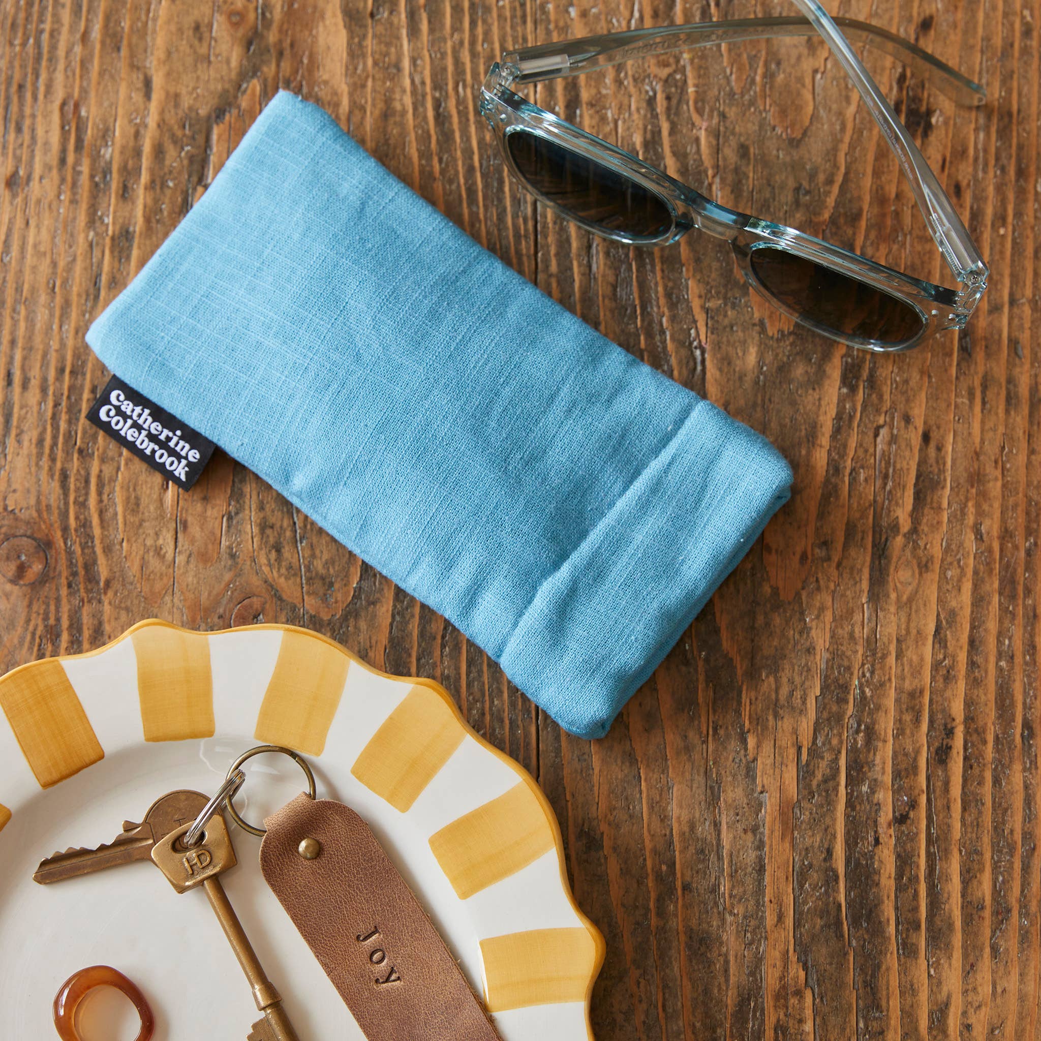 Blue glasses case with sunglasses on a wooden surface