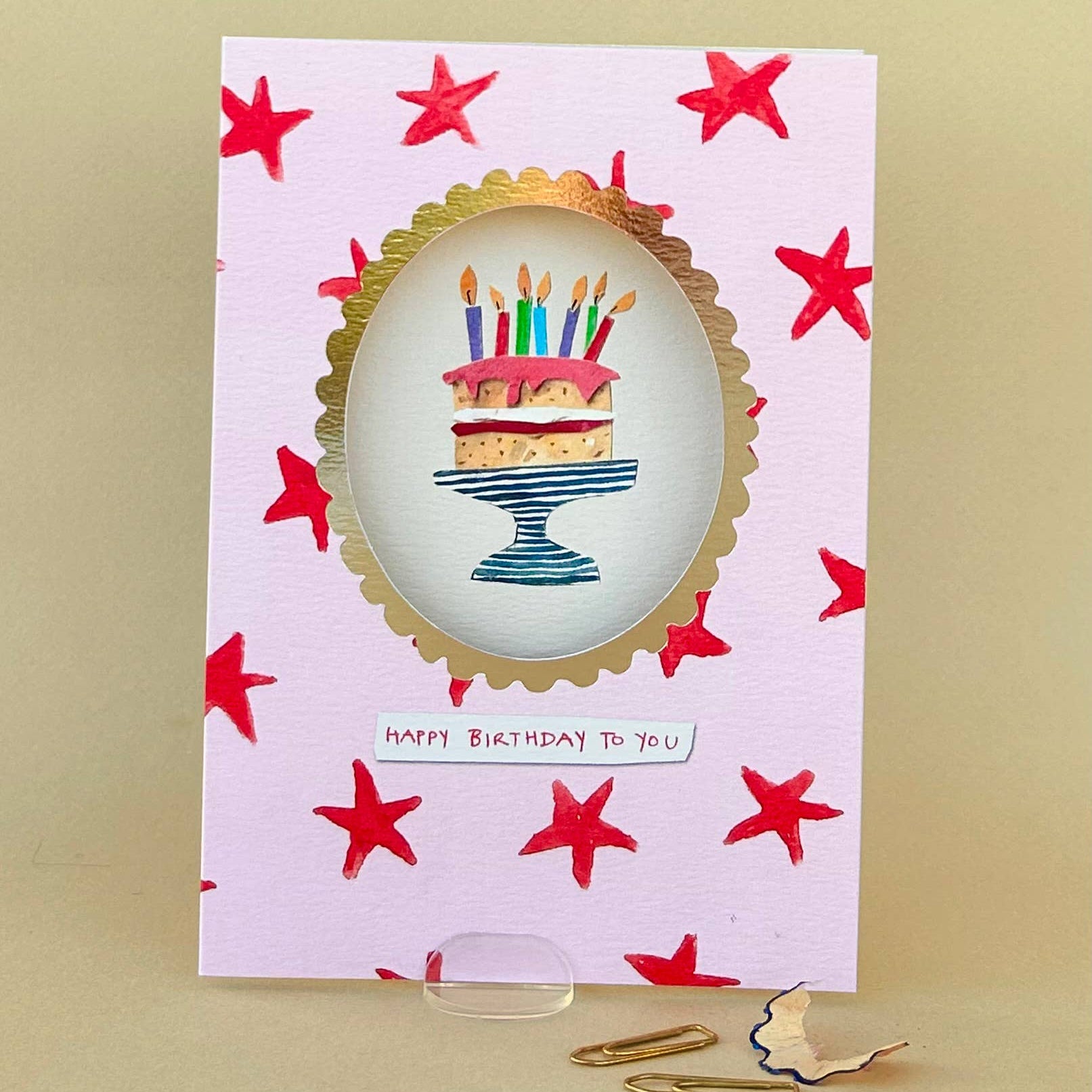 Birthday card with a cake illustration and red stars on a beige background