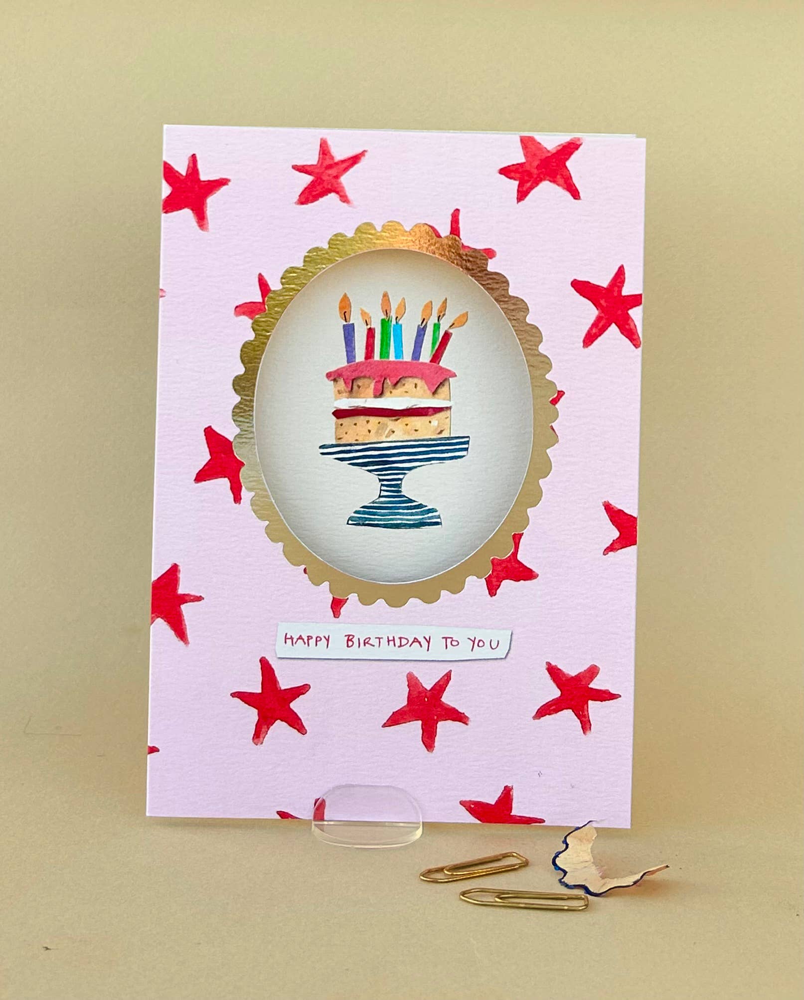 Birthday card with a cake illustration and red stars on a beige background