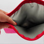 Close-up of a hand holding open a red zipper with gray interior.