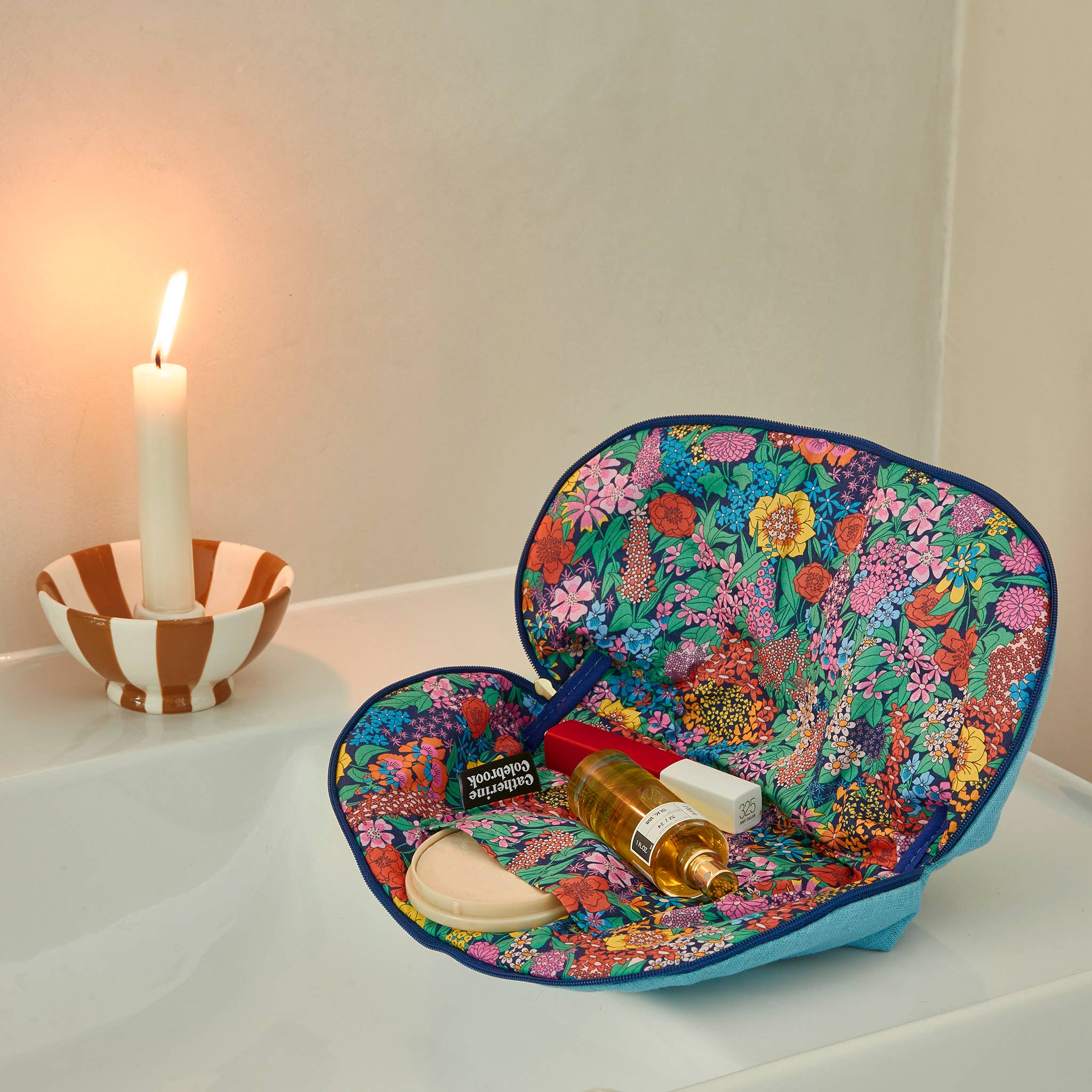 Floral-patterned tray with a candle and bottle on a white surface