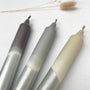 Three metallic markers on a white surface with dried plants in the background