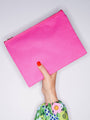 Pink pouch held by a hand with floral nail polish on a light gray background