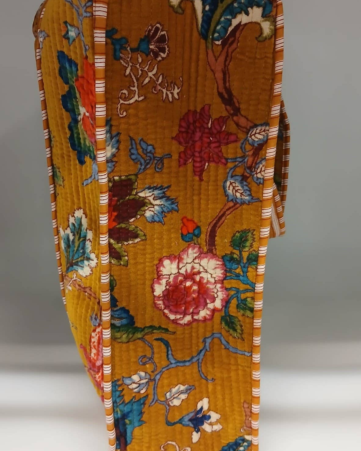 Decorative folded fabric with floral and bird patterns on a plain background