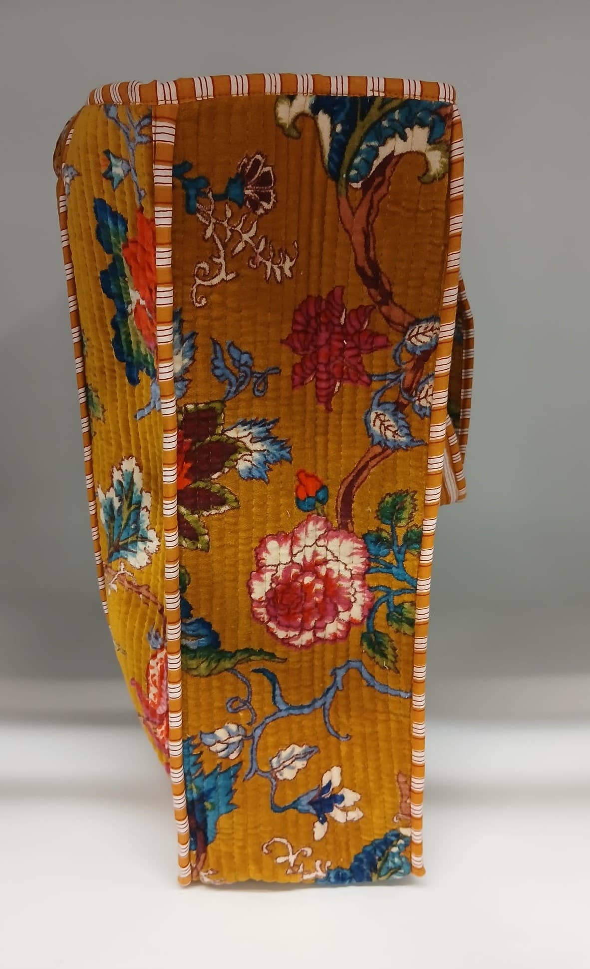 Decorative folded fabric with floral and bird patterns on a plain background