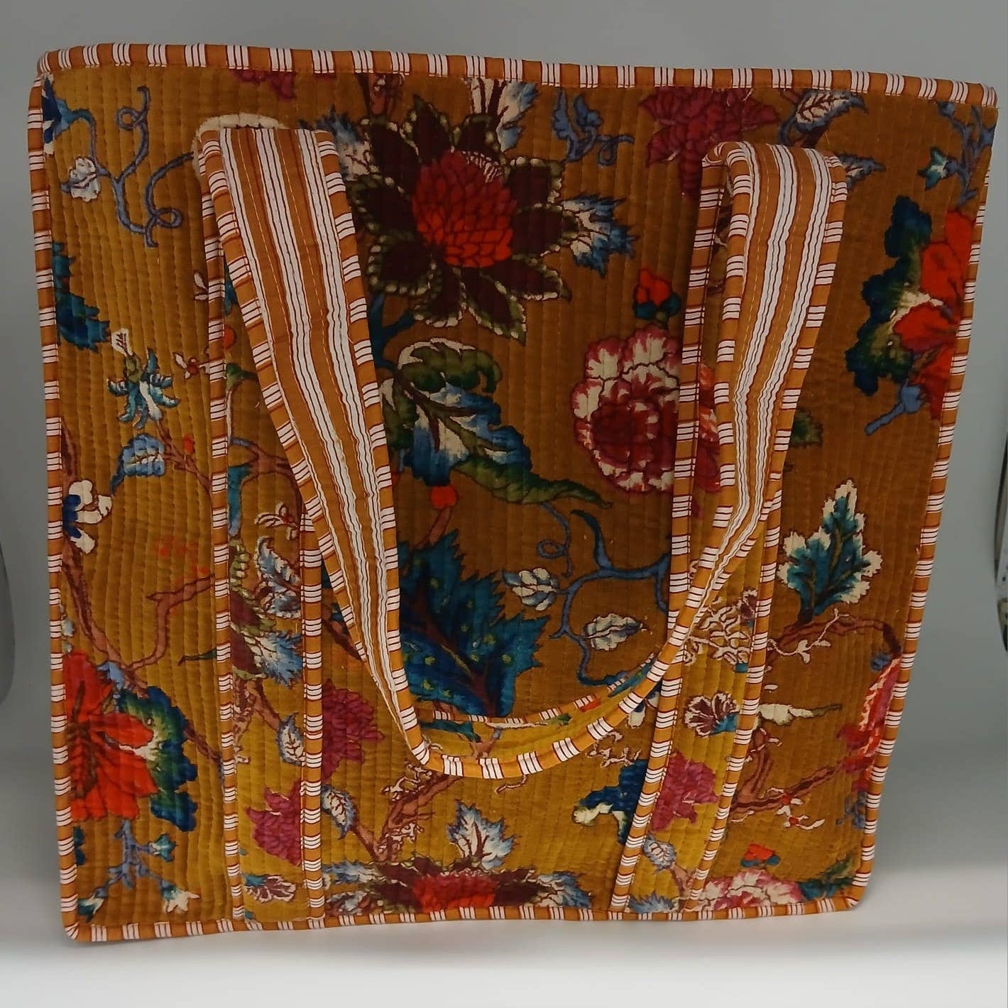 Floral patterned fabric with a striped border on a gray background