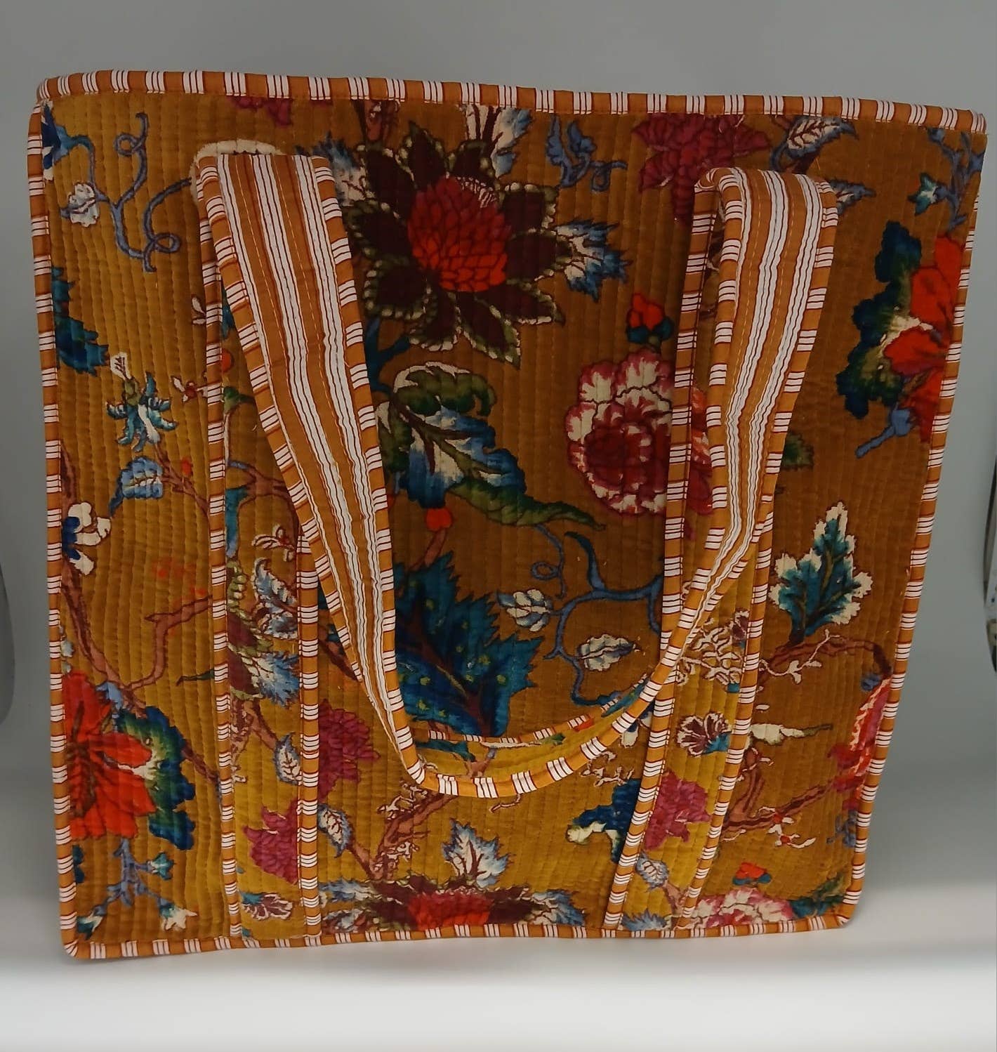 Floral patterned fabric with a striped border on a gray background