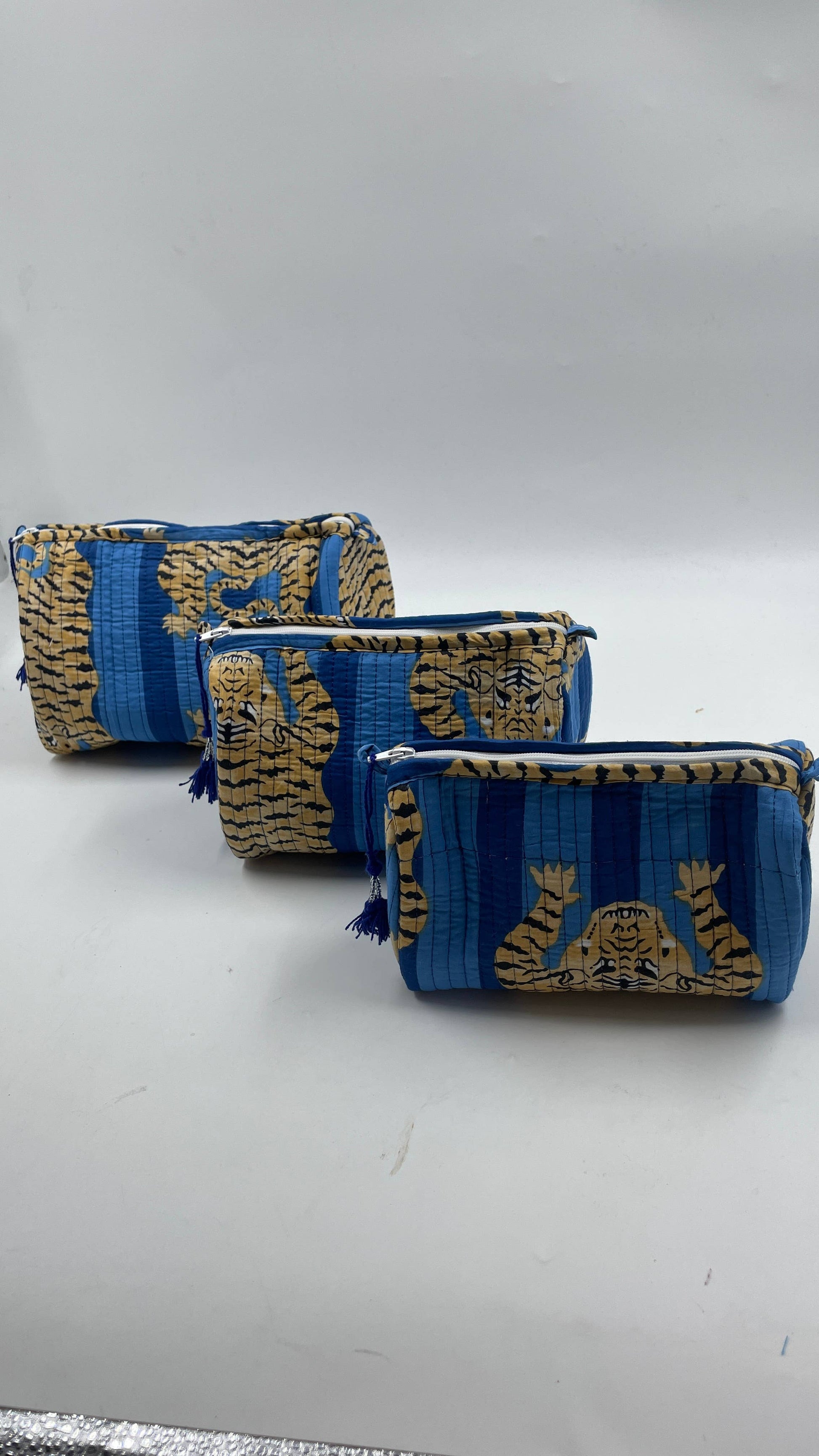Three blue and gold patterned pouches on a gray background