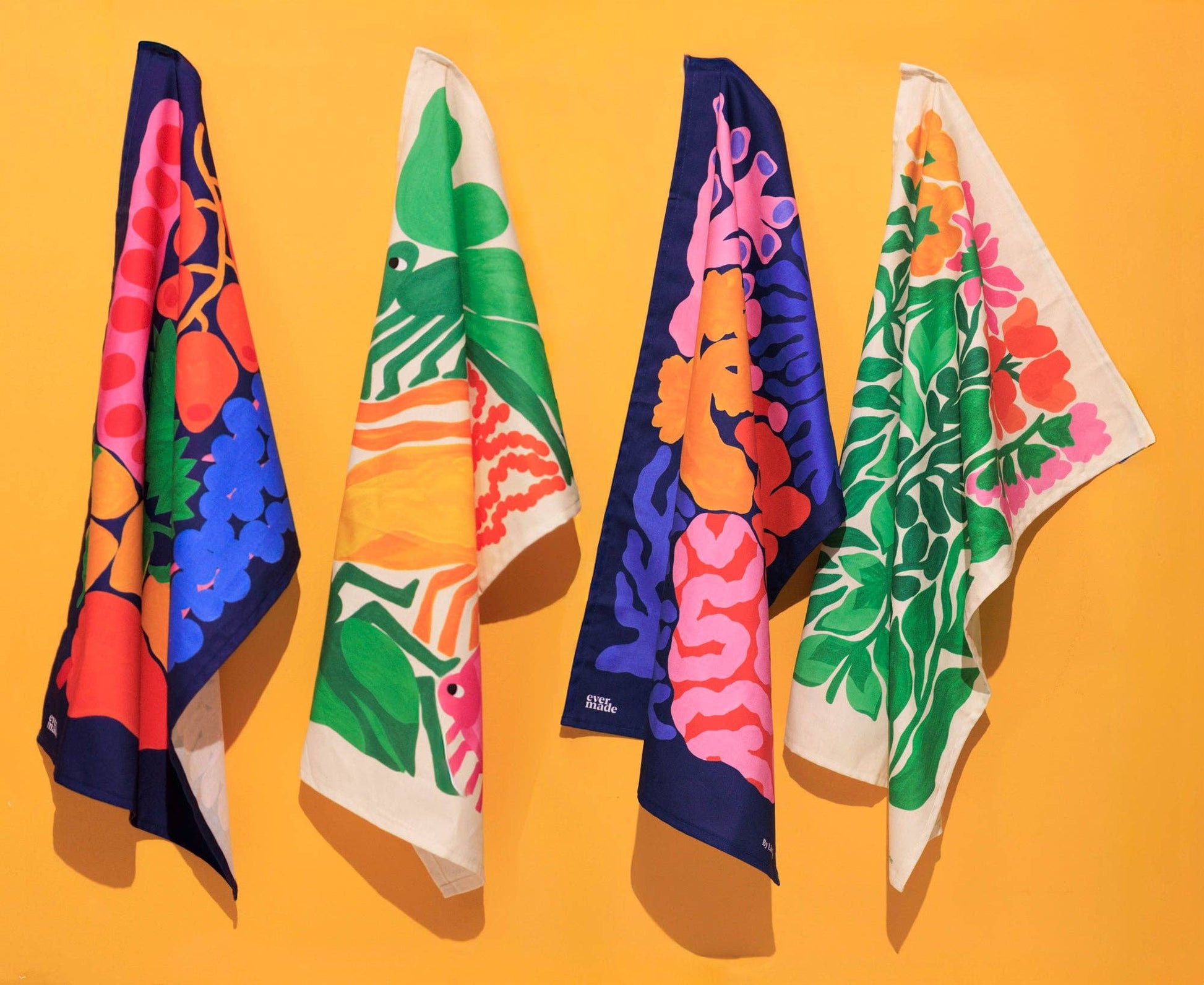 Four colorful scarves with floral and abstract patterns on a yellow background