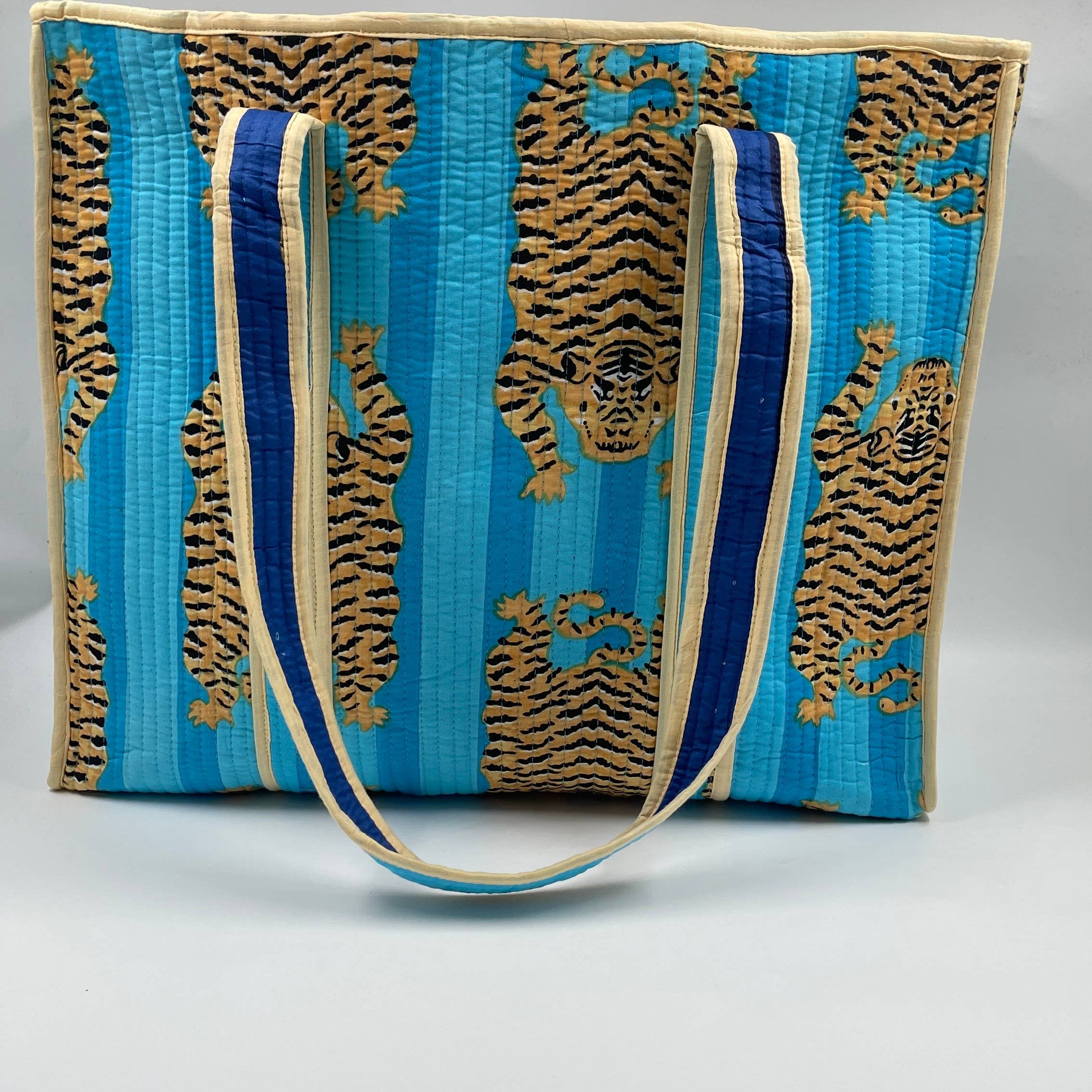 Blue and gold patterned bag with a strap on a gray background